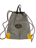 A Gucci handbag with a multicolor pattern, featuring a beige and yellow color scheme, a leather trim, and a brand logo on the front.